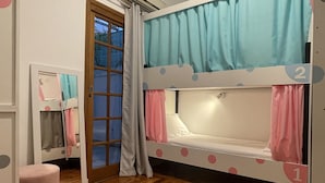 A room with a bunk bed, a small round table, a mirror, and a door leading outside. - Morada City Hostel (São Paulo)