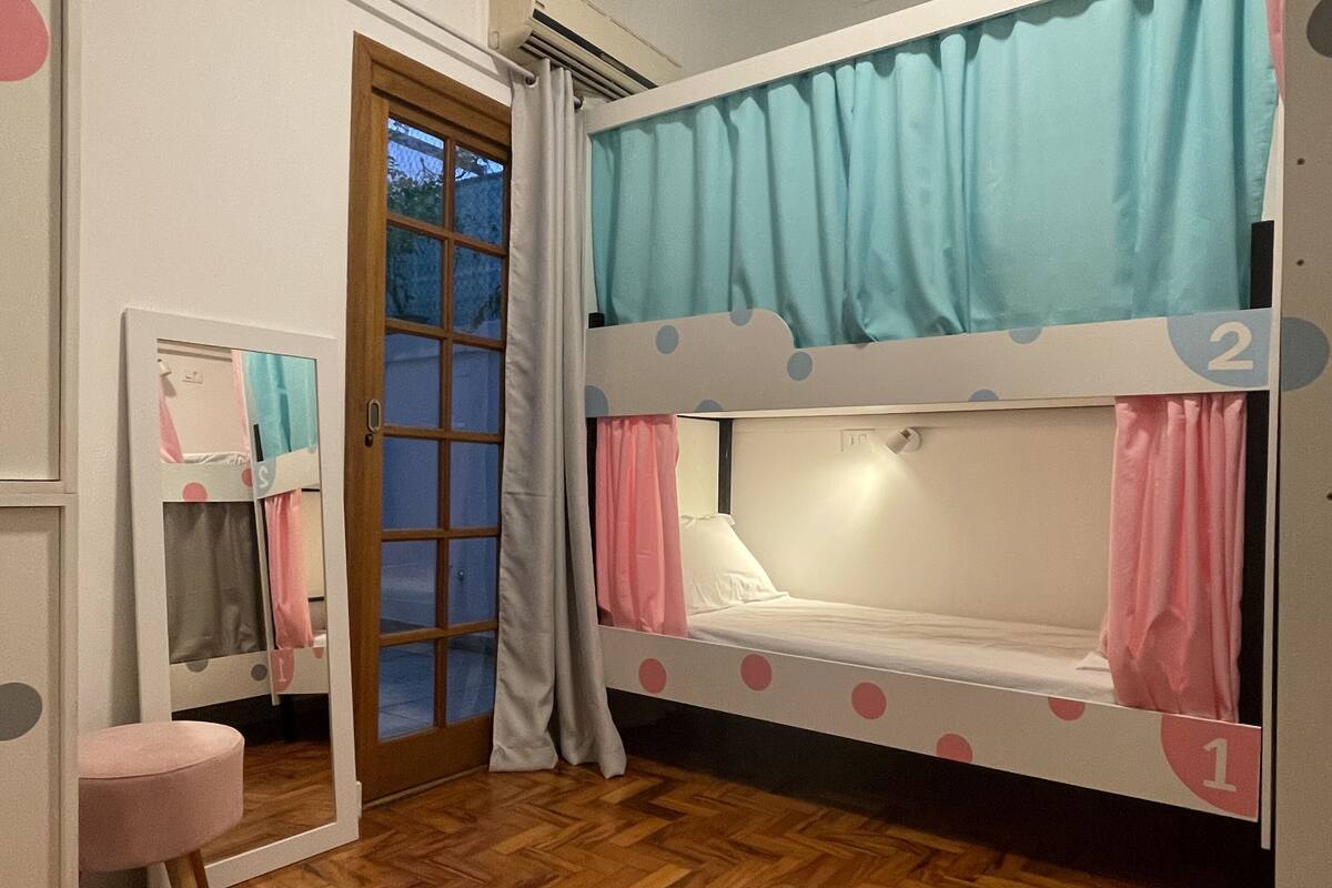 A room with a bunk bed, a small round table, a mirror, and a door leading outside.