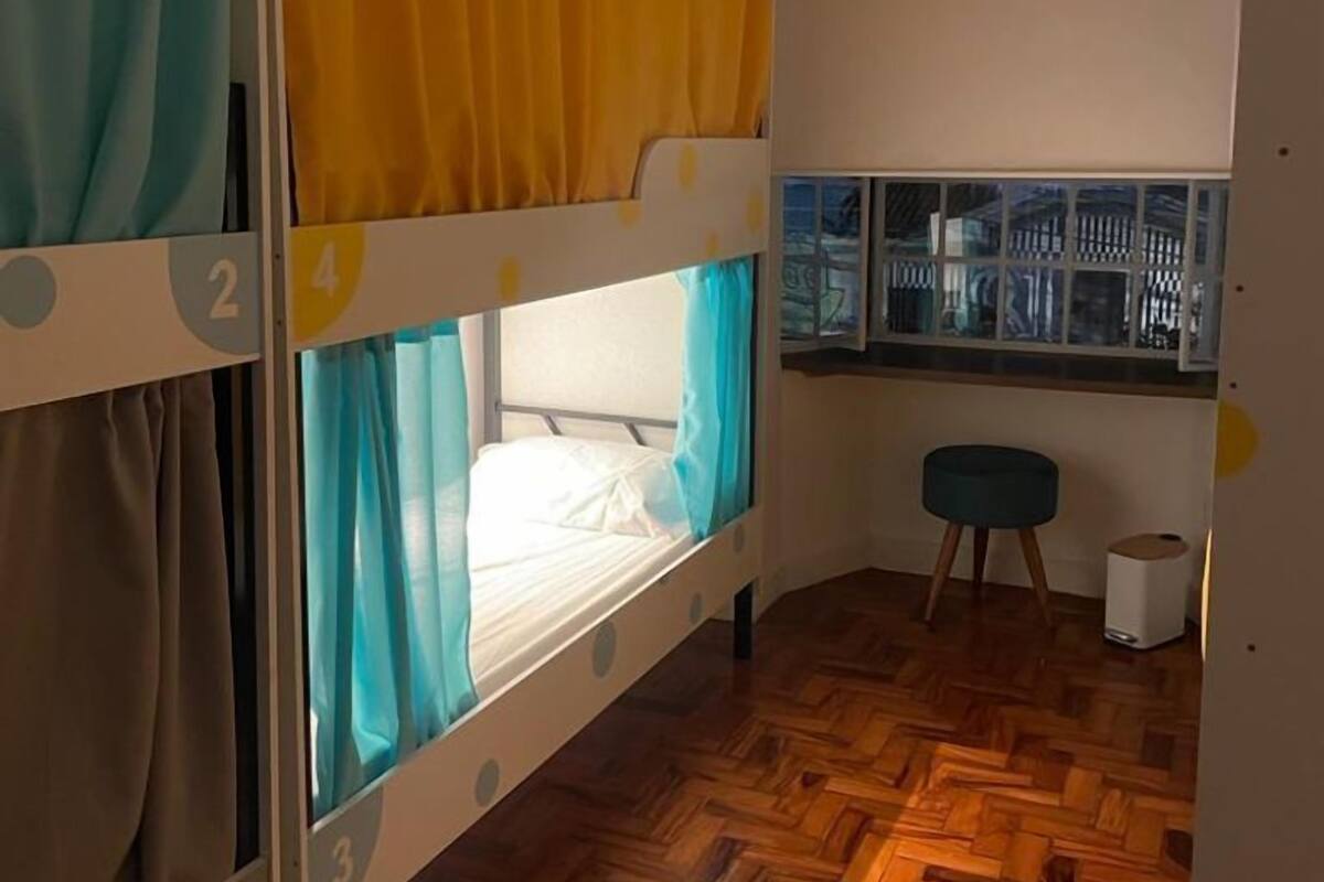 A bunk bed room with a window view, a small stool, and a trash bin.