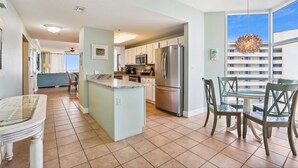 A modern kitchen with a central island, stainless steel appliances, and a dining area with a glass table and chairs.