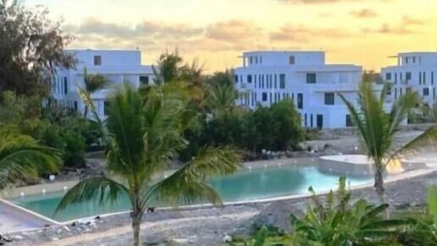 Ein Resort mit weißen Gebäuden, einem Swimmingpool und Palmen.