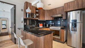 Eine moderne Küche mit Holzausstattung, Edelstahlgeräten und einer zentralen Kochinsel mit Barhocker.