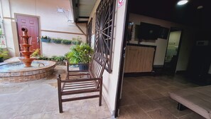 A courtyard with a fountain, potted plants, a wooden bench, and a tiled floor. - Aires frescos de Boquete (Alto Boquete)