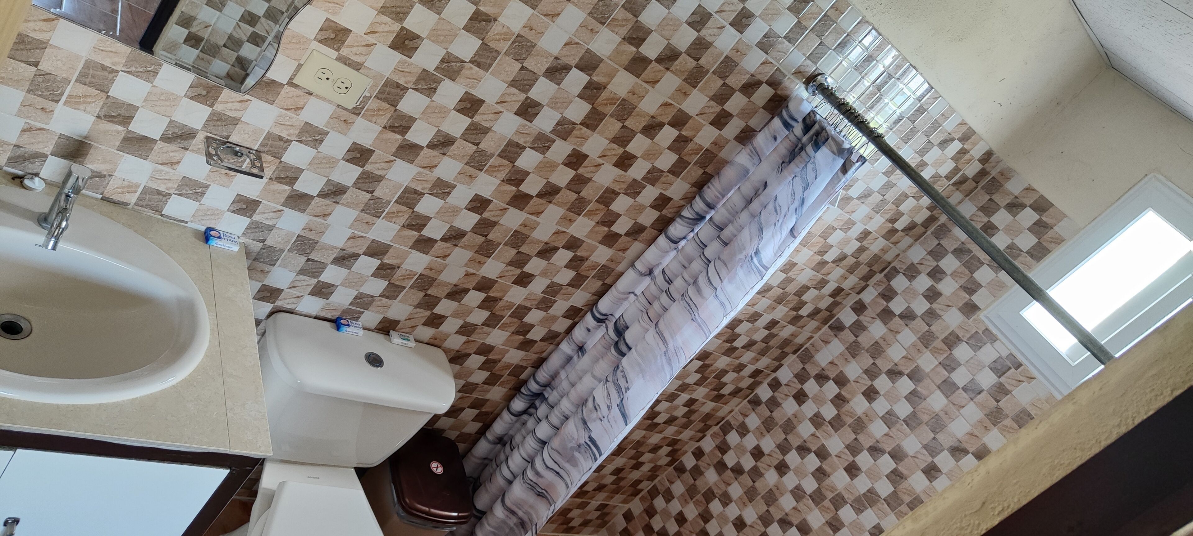 A bathroom with a checkered tile floor, a white sink, a toilet, and a shower curtain.