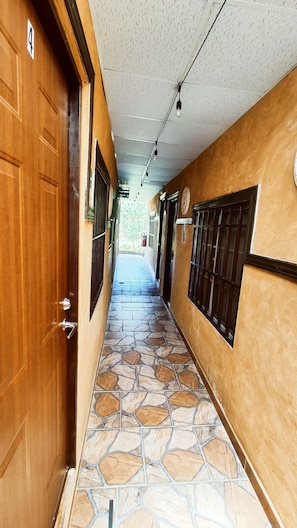 Stunning corridor with a geometric patterned floor, warm-toned walls, and metal doors and windows.