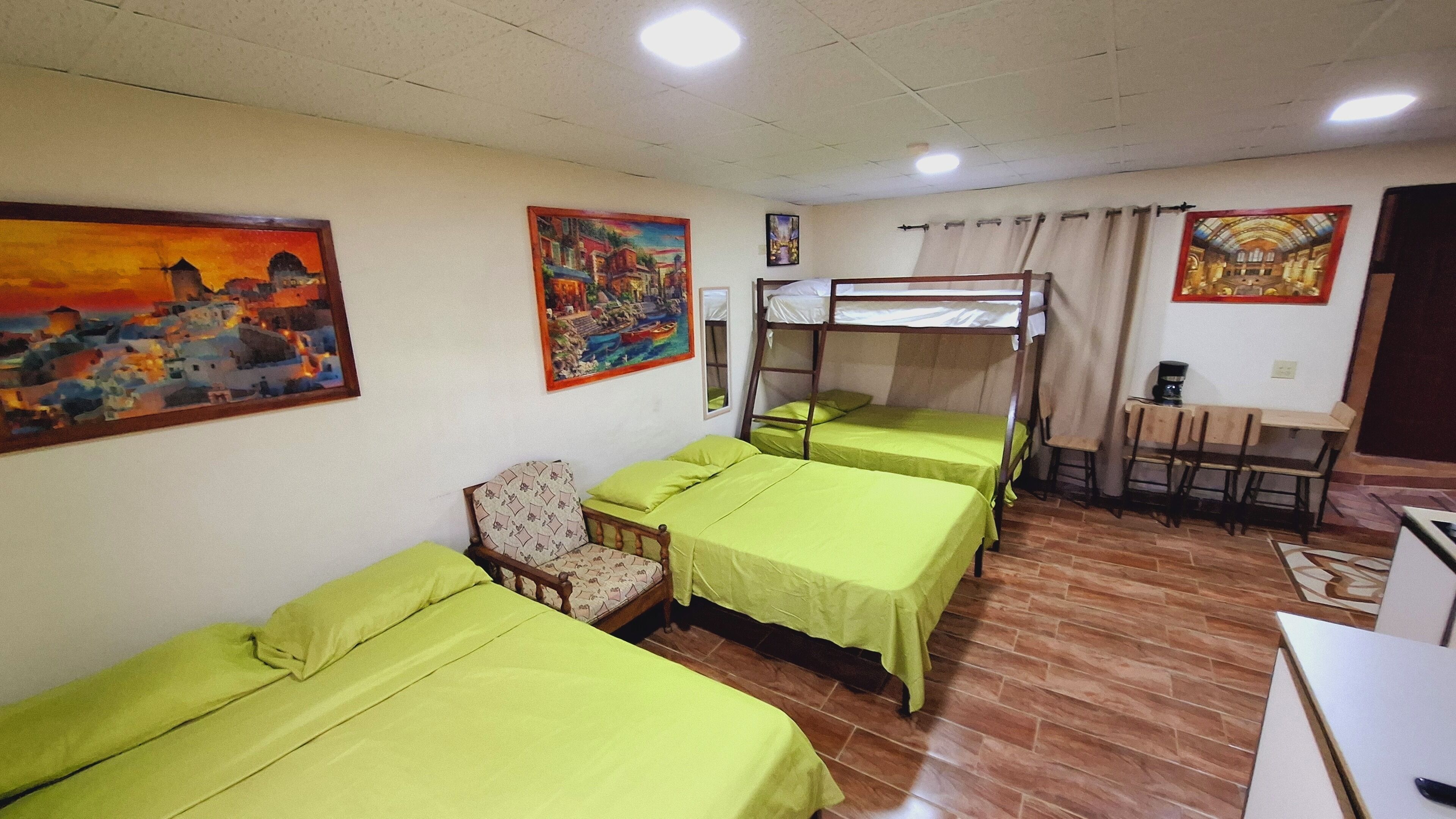 Un dormitorio con literas, un escritorio, una silla y obras de arte en las paredes.