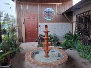 A hotel entrance with a wooden door, a neon sign, and a fountain. - Aires frescos de Boquete (Alto Boquete)