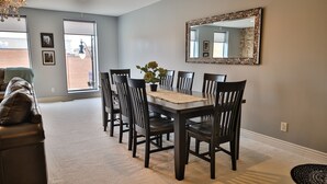 A dining area with a dark wooden table and chairs, a potted plant, and a large mirror on the wall. - 1 Bedroom Loft in Downtown Defiance! (Defiance)