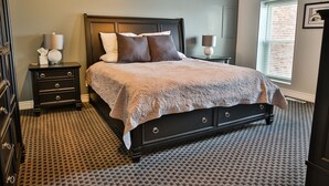 A bedroom with a bed, nightstands, a dresser, and a window with blinds. - 1 Bedroom Loft in Downtown Defiance! (Defiance)