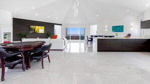 A spacious kitchen with a central island, a dining area with a round table, and a view to the outside. - Villa Farina in the Farrington (The Quarter)