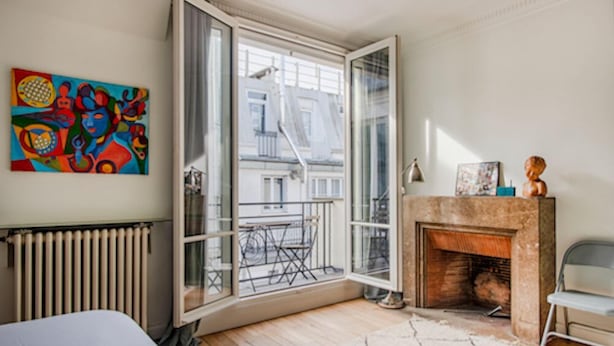 A room with a large window, a radiator, a fireplace, and a colorful abstract painting on the wall. - Courcelles Design Duplex (Paris)