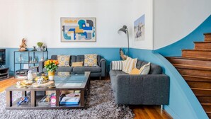 A living room with a grey sofa, a coffee table, and a blue accent wall. - Courcelles Design Duplex (Paris)