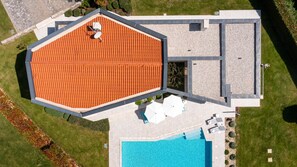 A modern building with a hexagonal roof, a swimming pool, and a landscaped garden. - Villa Nada by Villas Guide (Kringa)