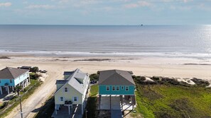 Ein Küsteneigentum mit Blick auf den Strand, ein zweistöckiges Haus und ein separates Gebäude mit einer überdachten Veranda.