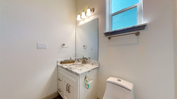 A bathroom with a marble sink, a large mirror, a towel rack, and a toilet.