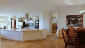 A spacious kitchen with a central island, white cabinetry, and a dining area with a chandelier. - Housekeeping BBQ Pool 4 TVs Garden Oceanview Villa Casa Sol Azul (Tempate)