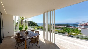 A balcony with a table and chairs, a view of the sea, and a cityscape in the background. - Villa Mar by Villas Guide (Palit)