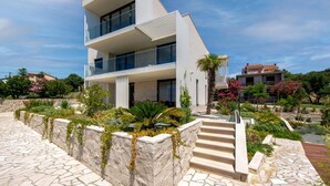 A modern multi-story building with a stone facade, a balcony, and a landscaped garden with steps leading to the entrance. - Villa Mar by Villas Guide (Palit)