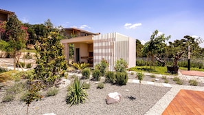 Une maison moderne dotée d’un patio, d’un jardin et d’un mur en pierre.