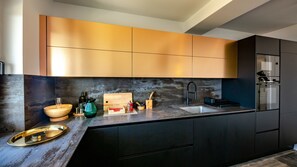 A modern kitchen with dark cabinets, a marble countertop, and a built-in sink. - Villa Mar by Villas Guide (Palit)