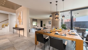 A modern dining area with a wooden table, black chairs, and pendant lighting. - Villa Aruna by Villas Guide (Pula)