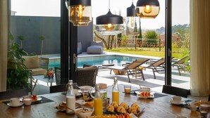 A breakfast setup with a pool view, lounge chairs, and a dining table with breakfast items. - Villa Aruna by Villas Guide (Pula)