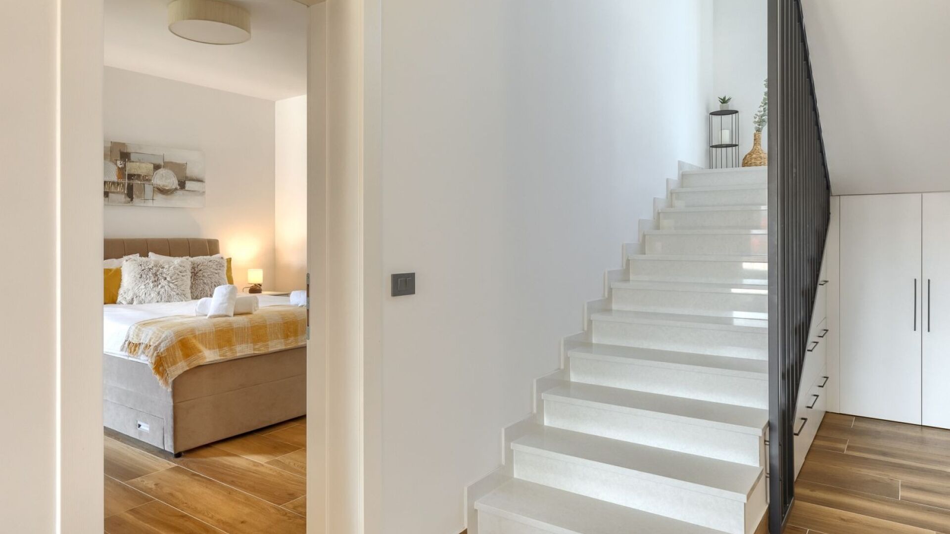Habitació d'hotel moderna amb llit, taula de nit i una escala que porta a un armari.