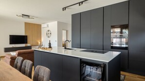 Een moderne keuken met een centraal eiland, een ingebouwde oven en een groot raam.
