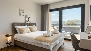 Een moderne hotelkamer met een groot bed, een bureau en uitzicht op de stad.