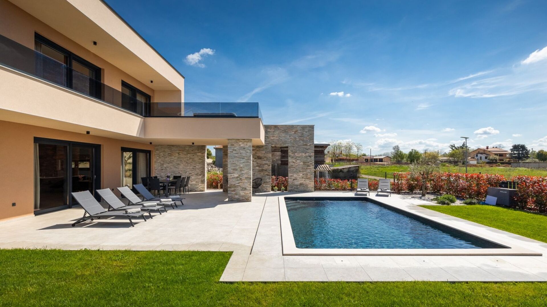 A modern two-story house with a swimming pool, outdoor seating, and a well-maintained garden.