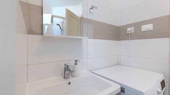 A modern bathroom with a large sink, a mirror, and a shower.