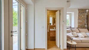 A modern interior with a wooden floor, a beige sofa, a small table, and a stone wall. - Villa Casa Mavretici by Villas Guide (Livade)