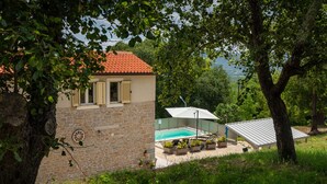 A stone building with a tiled roof, a swimming pool, and potted plants. - Villa Casa Mavretici by Villas Guide (Livade)