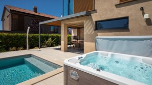 Ein Schwimmbad und ein Whirlpool vor einem modernen Haus.