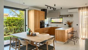 Eine moderne Küche mit Holzausstattung, einer zentralen Kochinsel und einem Essbereich mit Tisch und Stühlen.