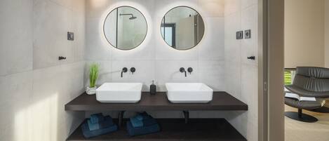 A modern bathroom with two sinks, a mirror, and a bench below.