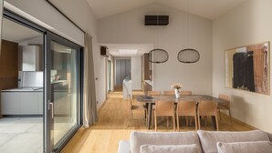 Une cuisine moderne avec une porte en verre, un coin repas doté d’une table en marbre et un grand tableau abstrait accroché au mur.