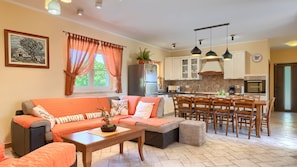 A cozy living room with a sofa, coffee table, and dining area with chairs and a table.