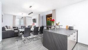 Een moderne keuken met een eetgedeelte, grijze meubels en een groot raam.