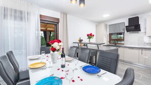 A modern kitchen and dining area with a large window, a dining table set for four, and a kitchen counter. - Villa Bibali Istra by Villas Guide (Bibali)