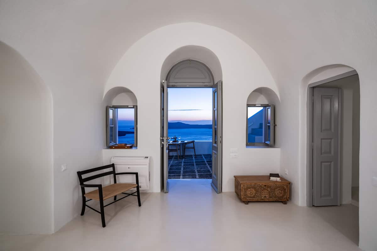Un pasillo con paredes blancas, un arco de entrada a un balcón con vista al mar.
