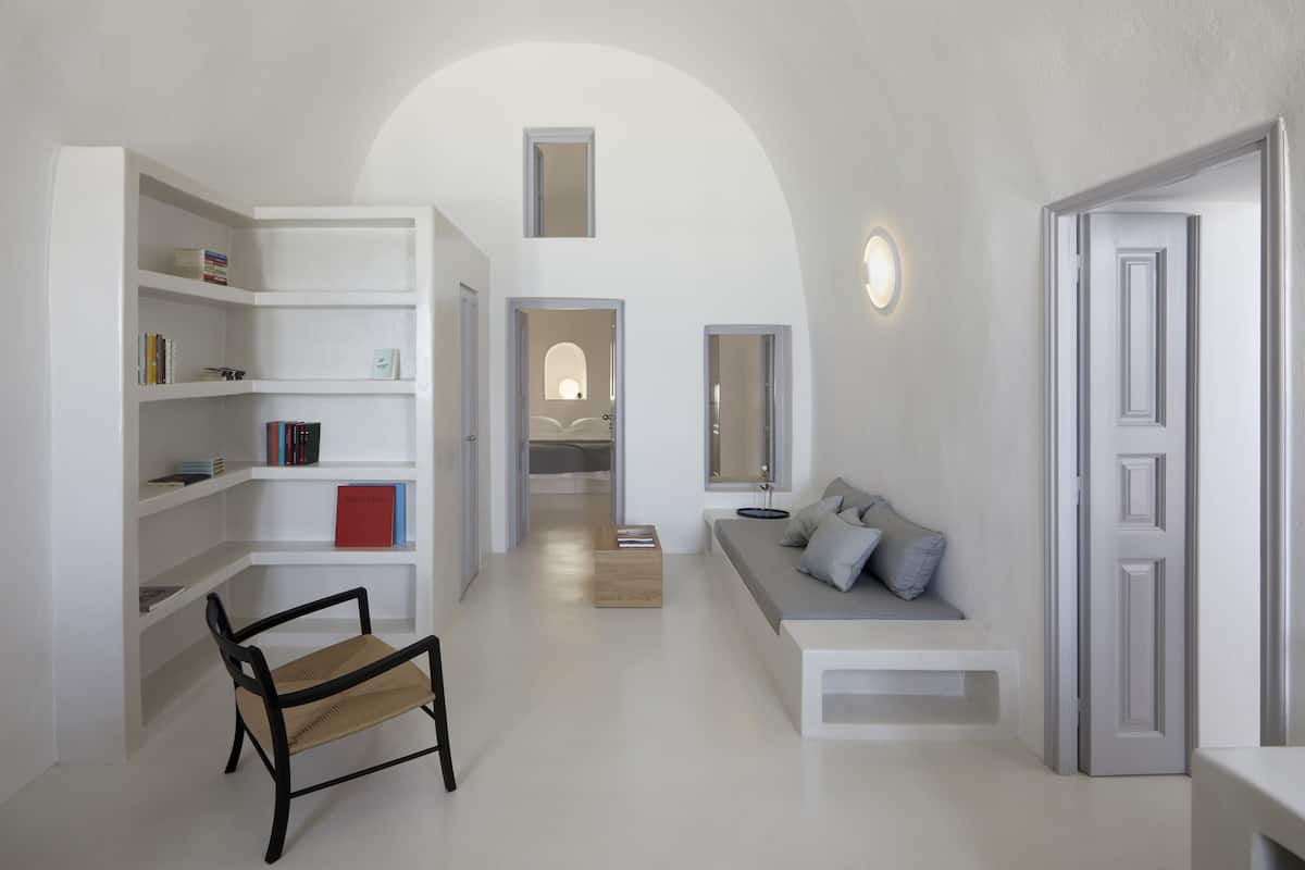 Una habitación moderna y minimalista con una estantería empotrada, un banco y una zona de estar con cojines.