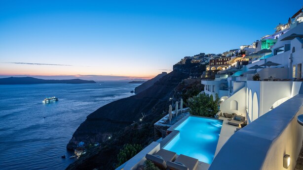 A coastal hotel with a pool overlooking the sea, a cliffside view, and a restaurant sign.