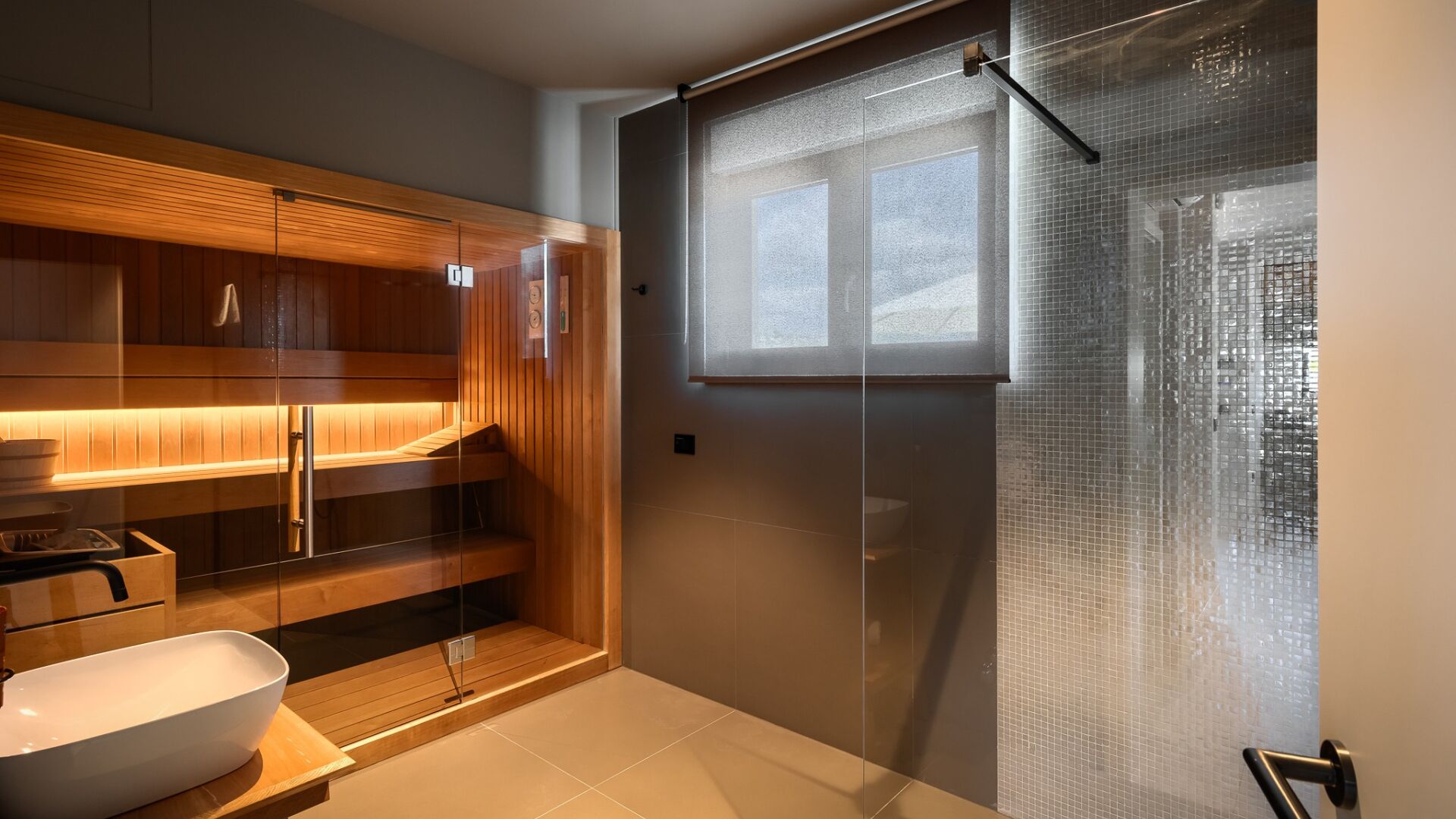 A modern bathroom with a glass shower enclosure, a wooden vanity, and a large sink.