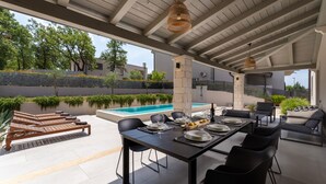 An outdoor dining area with a pool, stone pillars, and a view of the surrounding landscape. - Villa Molindrio by Villas Guide (Porec)