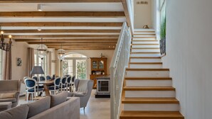 A spacious living area with a wooden staircase, a dining set, and a view of the outdoors. - Villa Monte by Villas Guide (Vižinada)