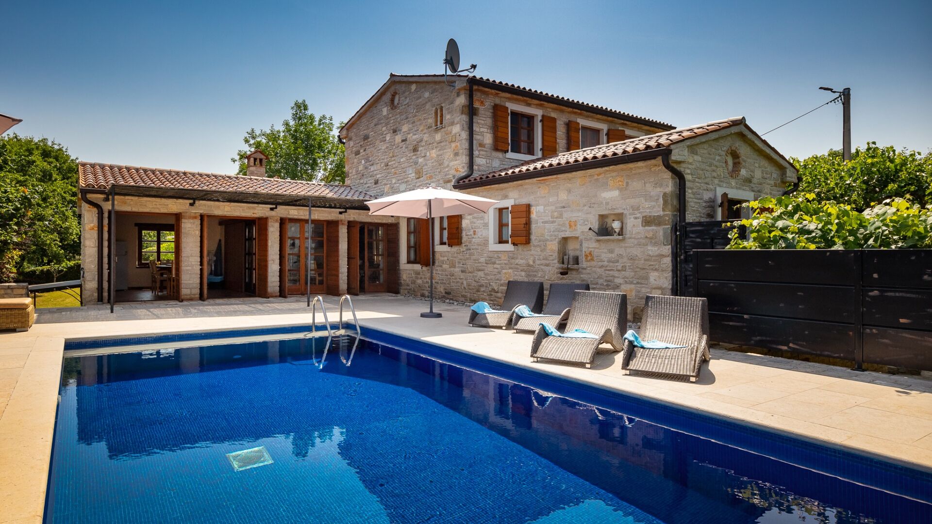 A stone house with a swimming pool, outdoor seating, and a garden.