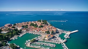 An aerial view of a coastal town with a historic center, marina, and a prominent bridge.
