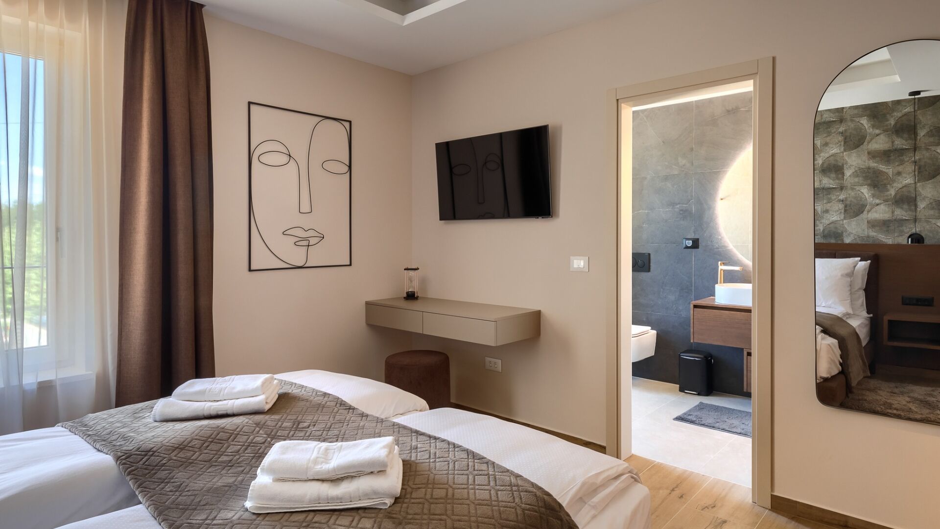 A hotel room with two beds, a bathroom, and a mirror.