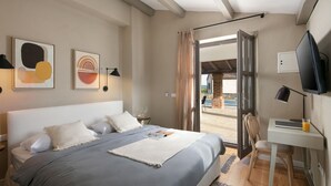 A bedroom with a bed, bedside tables, a desk, a chair, and a TV.